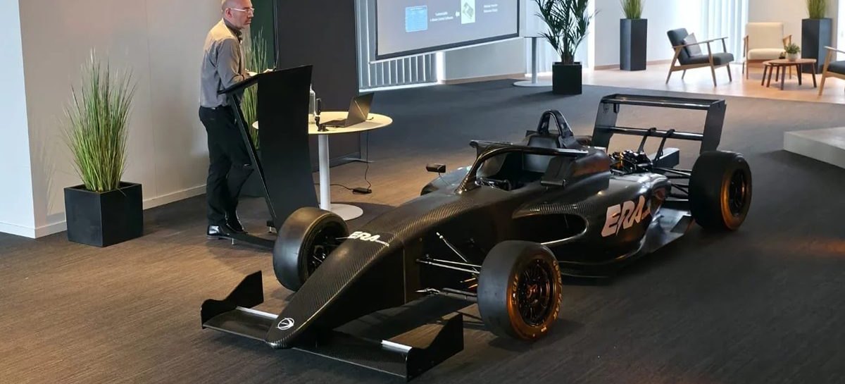 An electric formula car in bare carbon fibre at a technical presentation on inverter platforms.