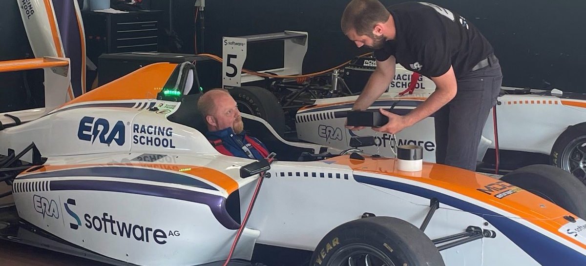 An engineer connecting diagnostic equipment to an electric formula car in the garage.